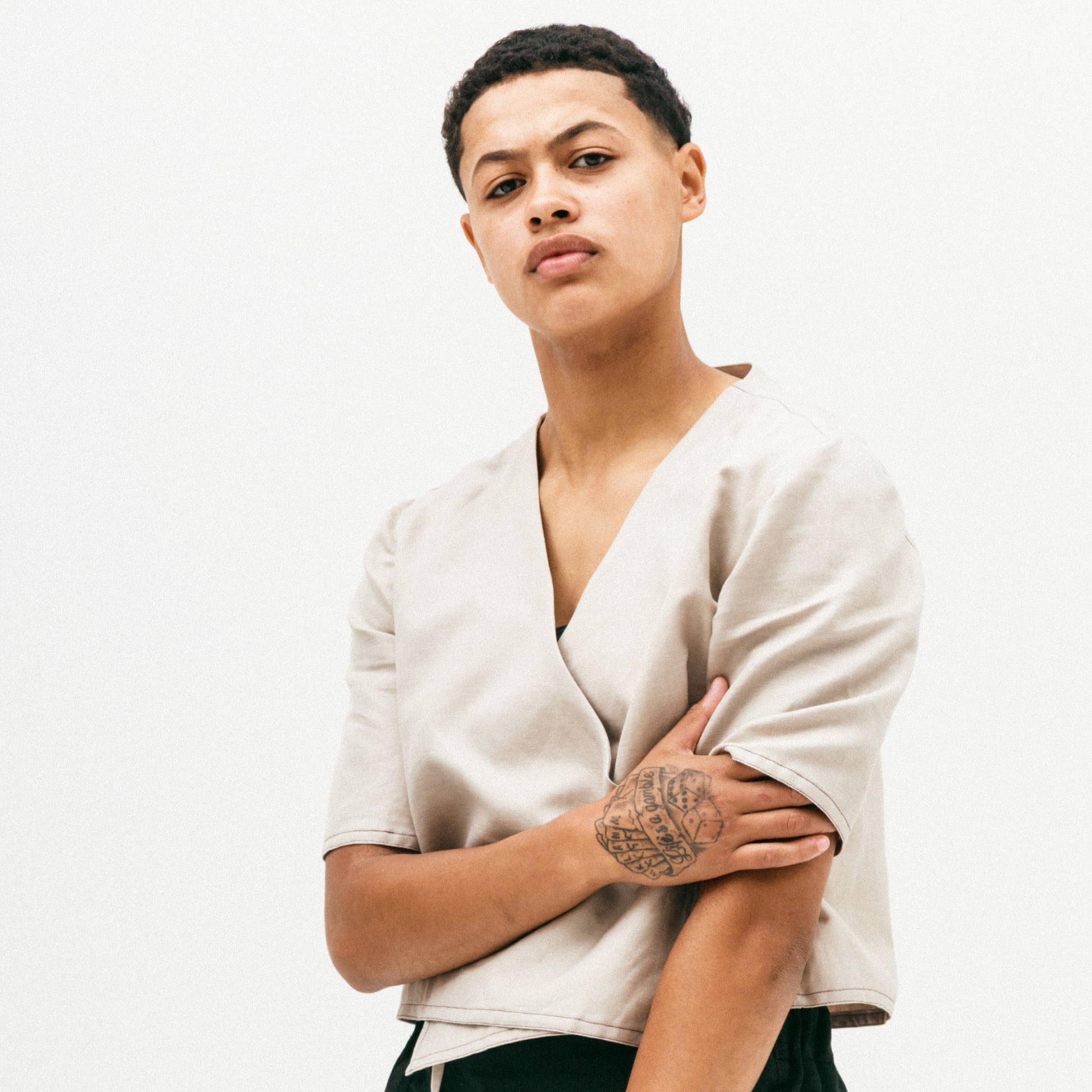 Person wearing a beige top with a plain background