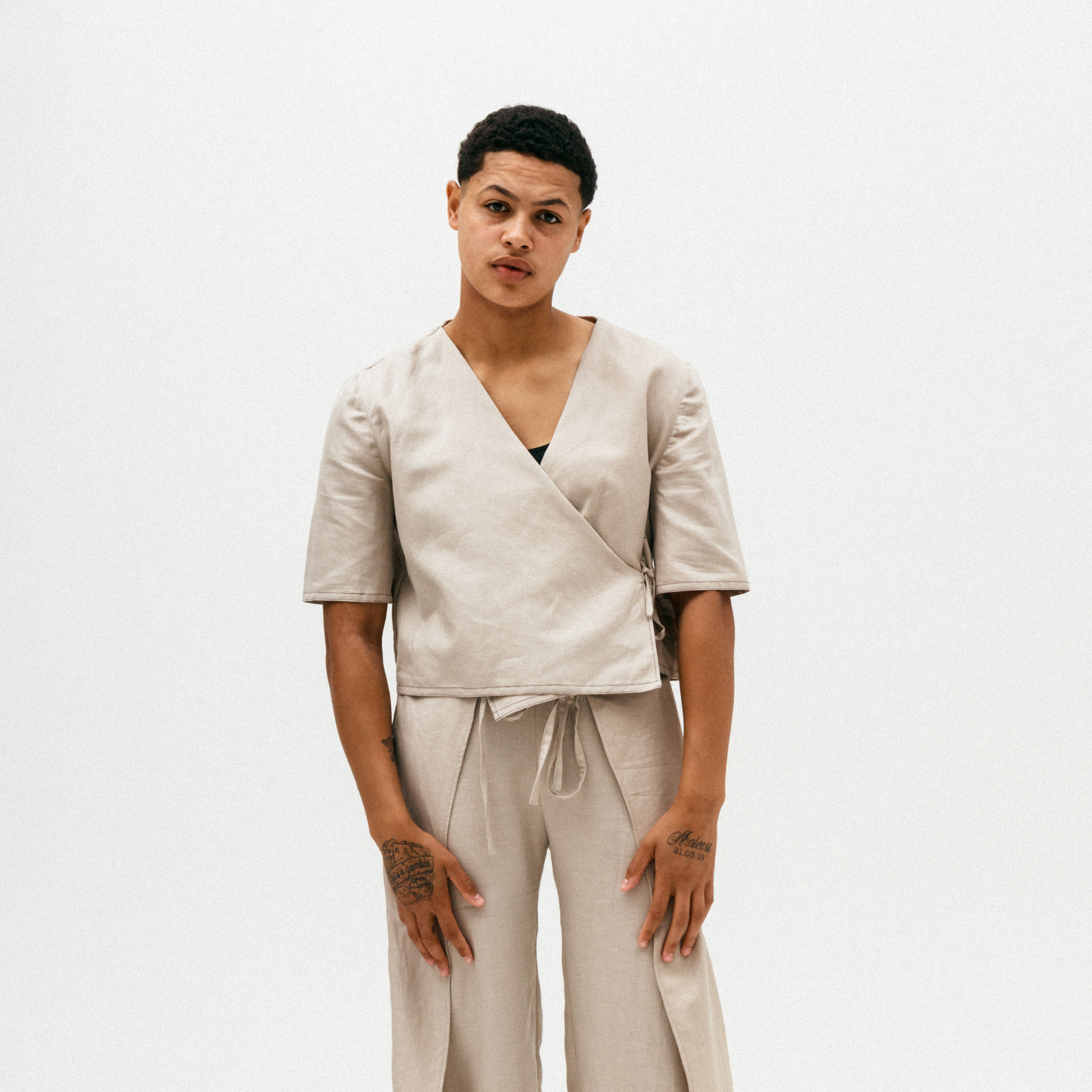 Person wearing a beige wrap top and pants on a white background