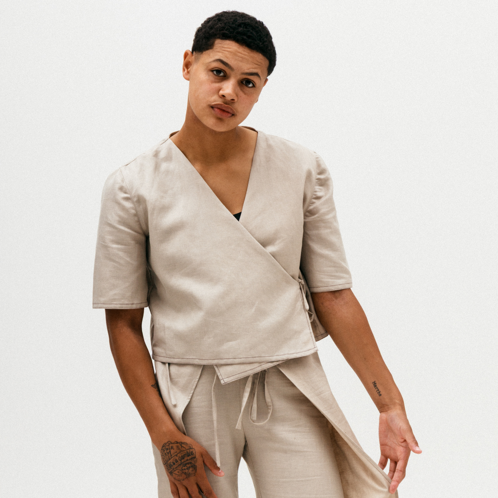 Person wearing a beige wrap top and pants on a plain background