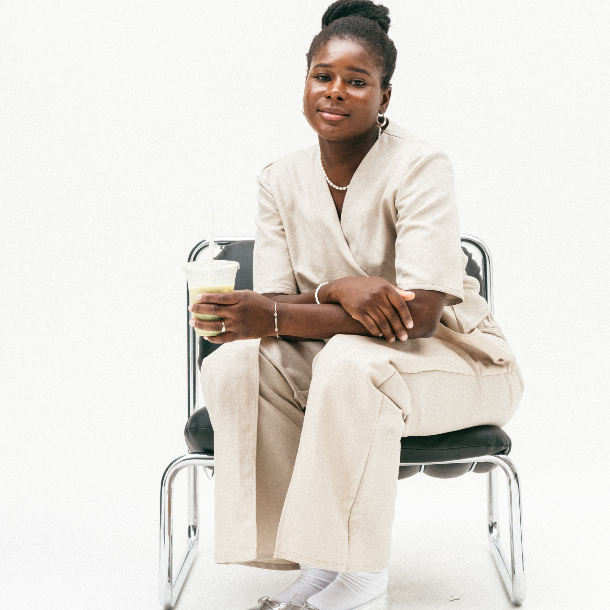 Woman in a beige suit sitting on a chair with a white background