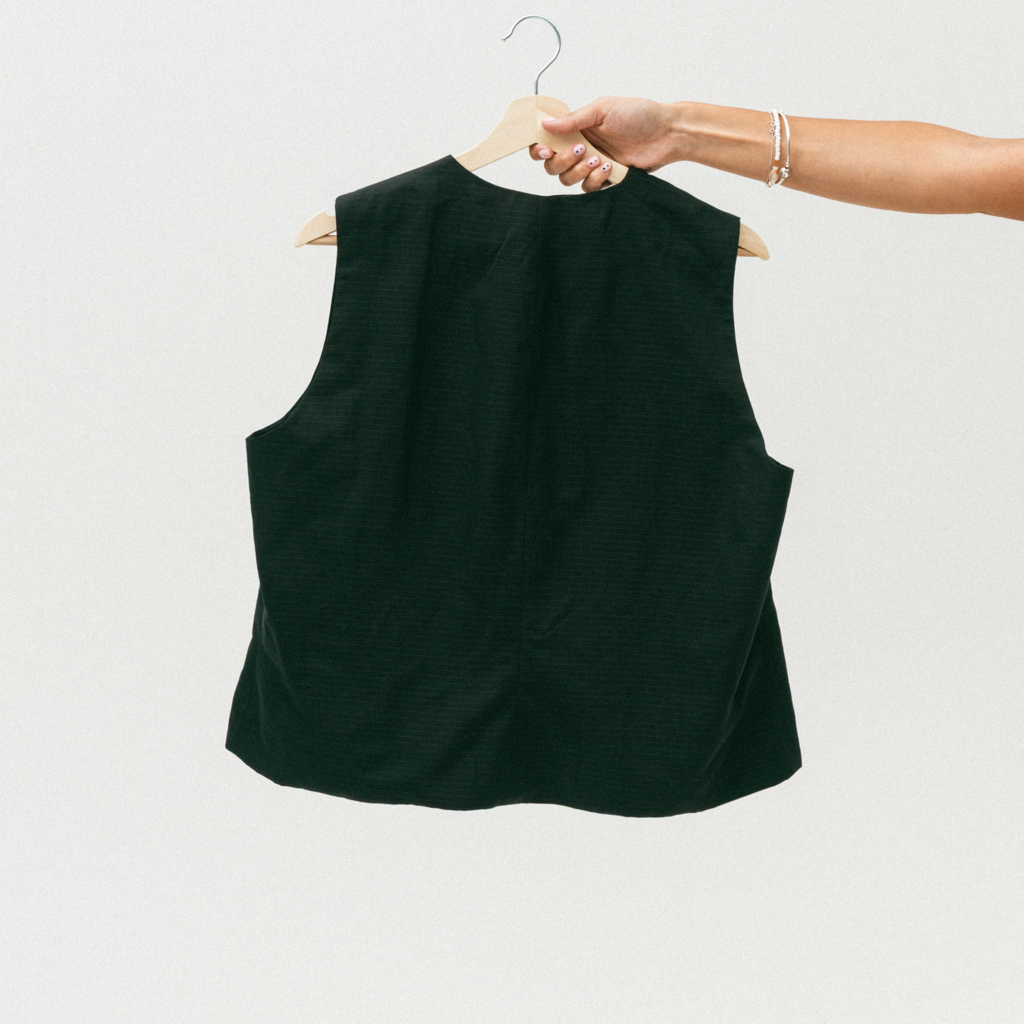 Black sleeveless top on a hanger against a white background