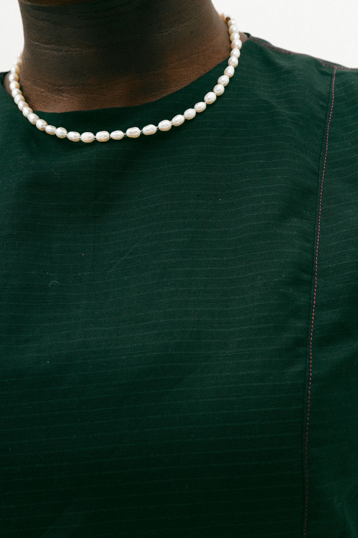 Person wearing a black top with a pearl necklace