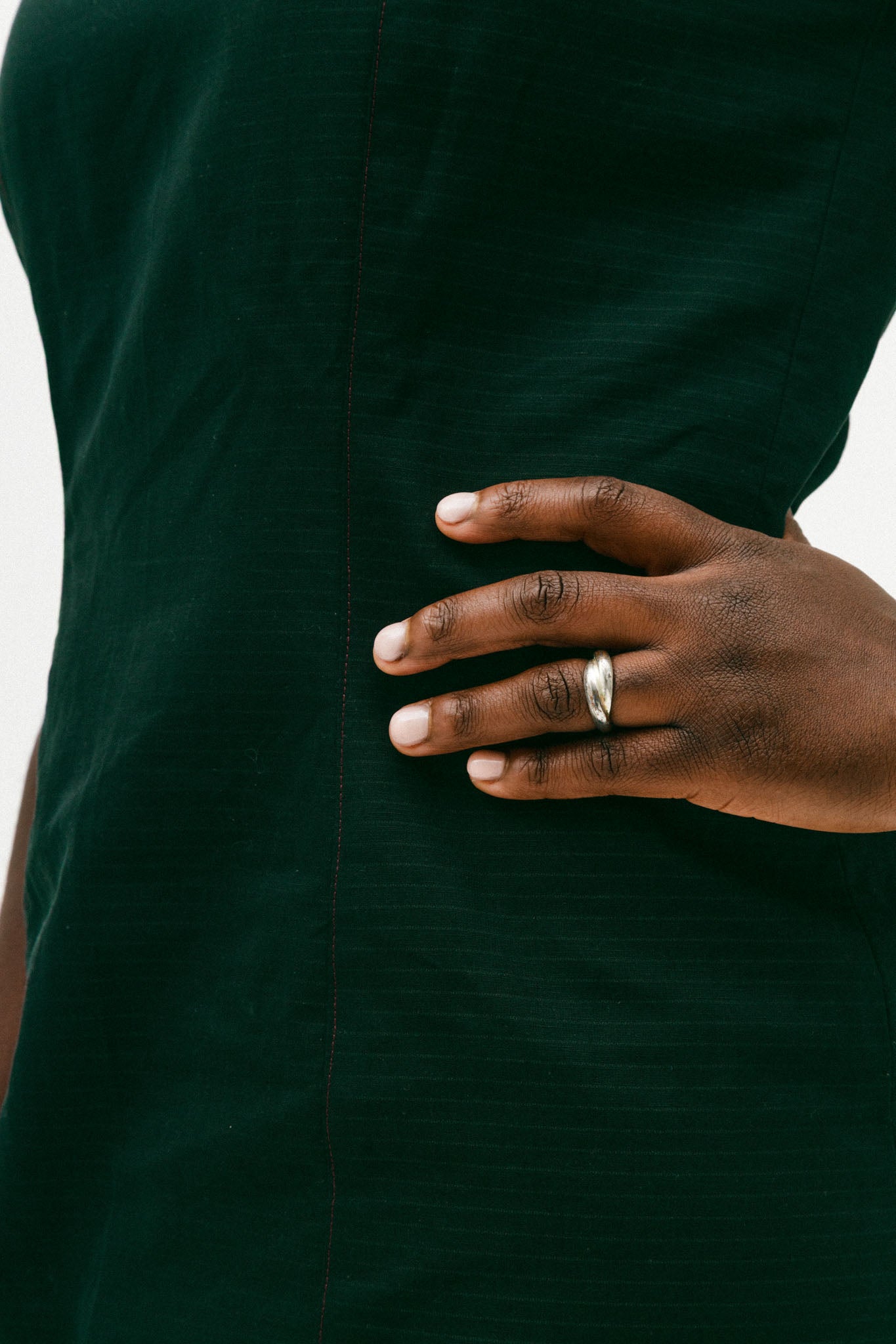 Person wearing a black dress with a hand on their hip, showing a ring.