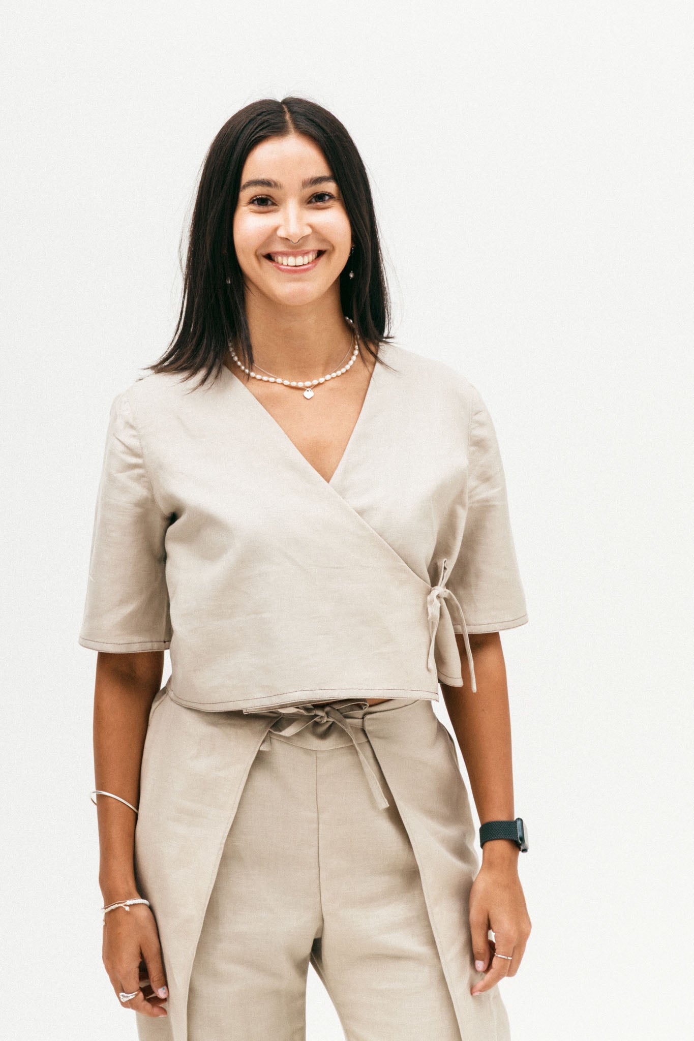 Woman wearing a beige wrap top and pants on a white background