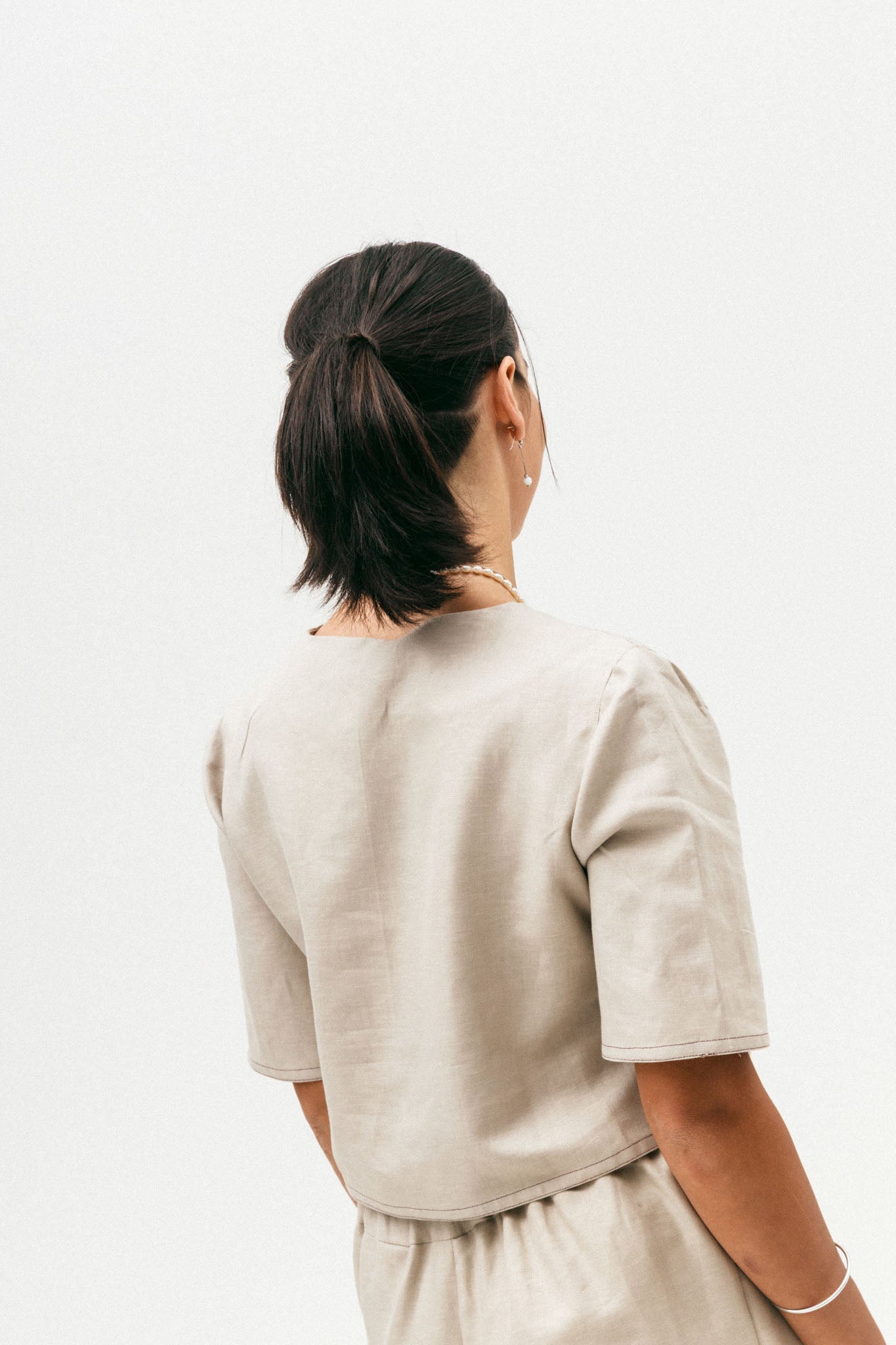 Person wearing a beige outfit on a plain background