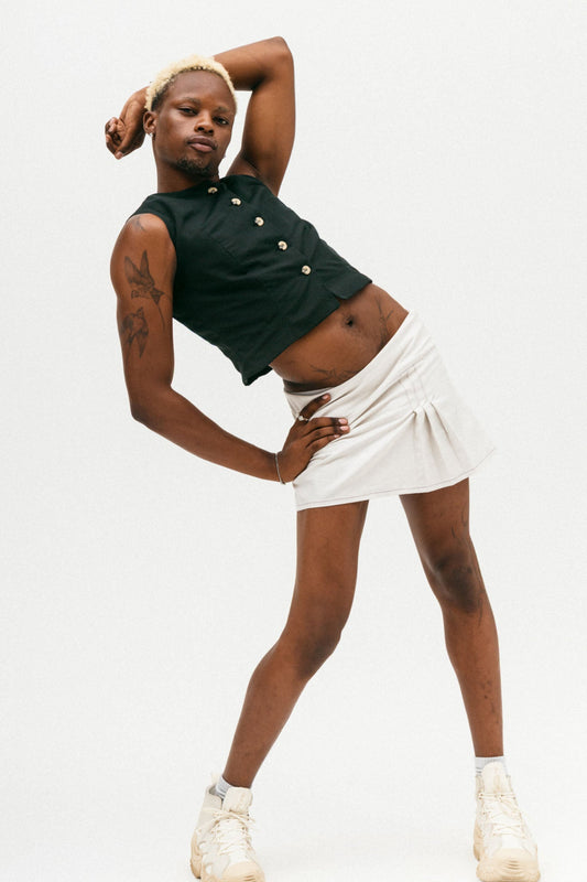 Person wearing a ziyou black sleeveless top with beige buttons and the white jumi skirt on a plain background